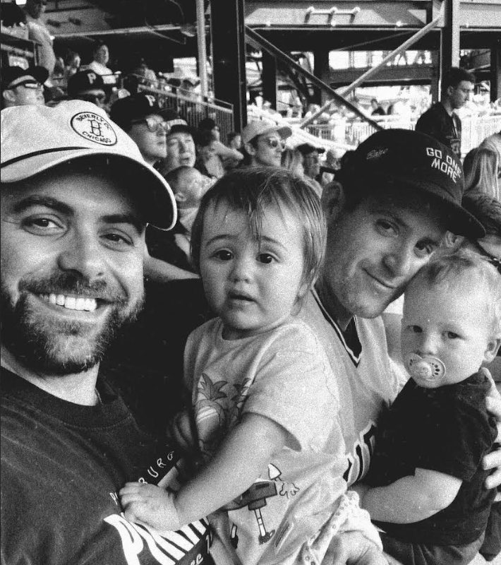 Two GRYT dads at the ballpark holding their kids